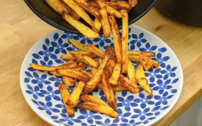 Złociste frytki, od cienkich shoestring po grubsze steak fries, wysypują się z patelni na talerz.