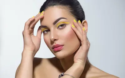 Mujer con un atrevido doble eyeliner amarillo y uñas a juego.