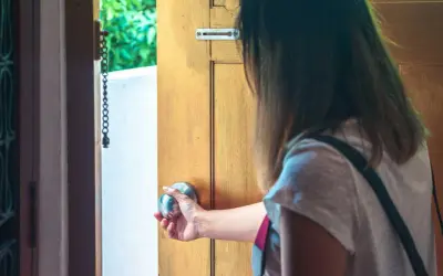 Mano che apre una porta, esitante, con l'ansia di uscire di casa che si fa sentire.
