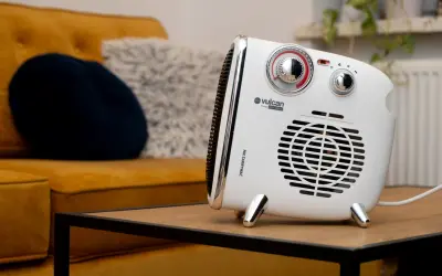 Kompaktowy grzejnik Vulcan, idealny do dogrzewania garażu, stoi na stoliku obok kanapy.
