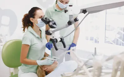 Dentystka z asystentką przy mikroskopie stomatologicznym, przygotowujące się do zabiegu, być może wyrywania ósemki.