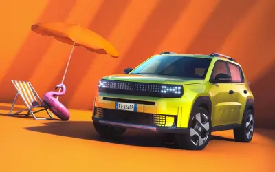 Nowy Fiat Panda w jaskrawym kolorze, gotowy na wakacje. Obok leżak, parasol i dmuchany flaming.