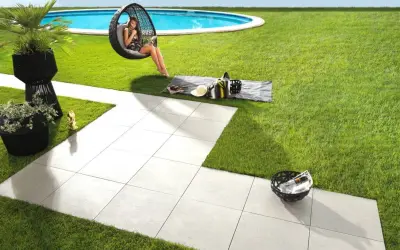 Posa di un pavimento in gres porcellanato con uno spessore ideale per esterni, che crea un'area relax con piscina e vista mare.
