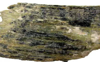 Szarozielony, włóknisty minerał z czarnymi wtrąceniami, przykład rzadkich minerałów.