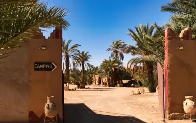 Ein Tor führt zu einem Campingplatz in Marokko, umgeben von Palmen. Ja, ist Marokko sicher für Reisende.