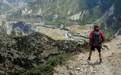 Widok z góry na dolinę i góry. Turysta z plecakiem zastanawia się, co zabrać w góry.