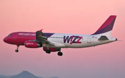 Samolot Wizz Air z różowym dziobem i fioletowym ogonem w locie. Wizz priority to komfort podróży.