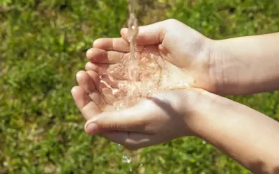 Mains d'enfant recevant un filet d'eau, une façon simple de rendre l'eau moins calcaire pour un usage quotidien.