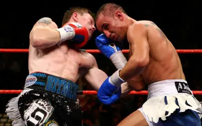 Two boxers exchange powerful boxing punches in the ring. One fighter lands a blow to the head, while the other attempts to counter.