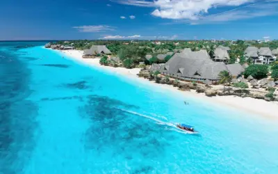 Idealny dzień, kiedy na Zanzibar. Turkusowa woda, biała plaża i łódź z turystami.
