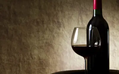 Butelka i kieliszek z czerwonym winem na tle. Czy czerwone wino się chłodzi?