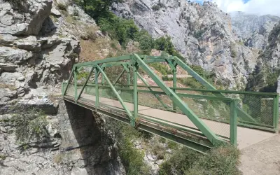 Puente Dobra, una estructura verde metálica cruza un desfiladero rocoso con vegetación.