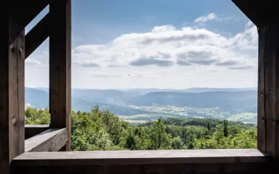 Widok z wieży widokowej na górę Cergową. Rozległa panorama Beskidu Niskiego, zielone lasy i pola, błękitne niebo z chmurami.