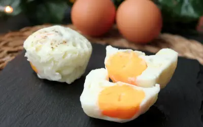 Huevos cocidos en microondas, uno entero y otro partido mostrando la yema naranja. Dos huevos enteros al fondo.