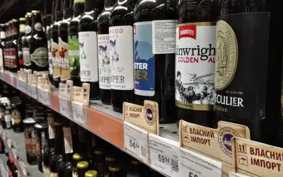 Rząd butelek piwa na półce sklepowej, niektóre z etykietami w języku ukraińskim, sugerującymi import. Widać ceny i nazwy piw, np. "Thwaites Wainwright Golden Ale".