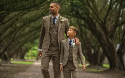 A man and boy in matching tweed suits, a perfect example of what formal attire means for a wedding.