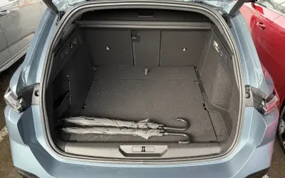Maletero abierto de un Peugeot 308 SW con dos paraguas negros. Las medidas del maletero son amplias para equipaje.