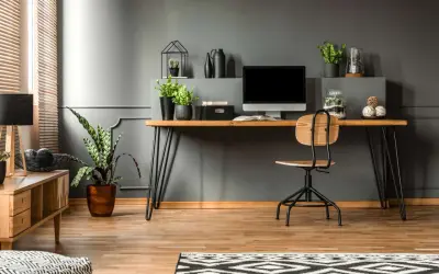 A modern desk setup with a computer, plants, and decorative items. This image shows how to hide cords on desk for a clean, organized workspace.