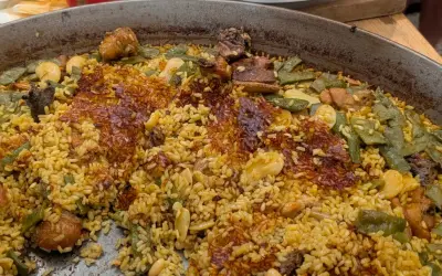 Paella de carne recién hecha, con arroz dorado, trozos de carne tierna, judías verdes y un delicioso socarrat crujiente.