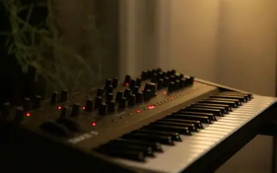 Elektroniczny instrument klawiszowy z licznymi pokrętłami i czerwonymi diodami, gotowy do tworzenia muzyki.