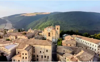 Borgo con torre dell'orologio, immerso nel verde delle colline. Chissà se è questo il borgo dei borghi vincitore.