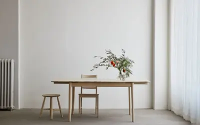 Ett ljust såpa ekbord med en vas med blommor och en pall.
