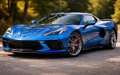 Niebieski Chevrolet Corvette C8, ikona wśród sportowych marek General Motors, prezentuje swoje dynamiczne linie na tle leśnej drogi.