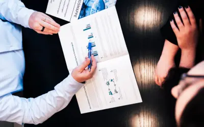 Zwei Personen besprechen ein Dokument über Private Equity und Rendite. Ein Mann zeigt mit einem Stift auf Diagramme.