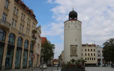 Der Reichenturm dominiert den Marienplatz Görlitz, flankiert von historischen Gebäuden und blühenden Blumenbeeten.