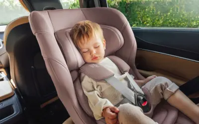 Schlafendes Kleinkind in einer rosafarbenen Babyschale. Die Frage "ab wann sitzschale bei kindern" wird hier durch das Bild beantwortet: ab Geburt.