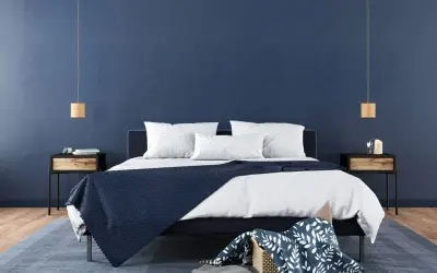 Ein modernes Schlafzimmer mit tiefblauen Wänden, die Ruhe und Harmonie ausstrahlen – eine ideale feng shui schlafzimmer farbe. Weiße Bettwäsche und dunkle Akzente schaffen ein stilvolles Ambiente.