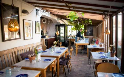 Mysig vinterträdgård med rustika bänkar och marmorbord, en av många annorlunda restauranger i Skåne.