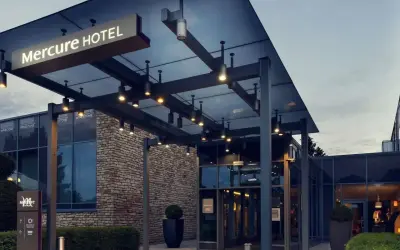 Nowoczesne wejście do hotelu Mercure w Gdańsku, z kamienną fasadą i oświetlonym zadaszeniem.