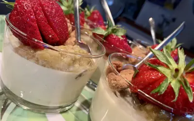 Fluffig pannacotta med rabarber och färska jordgubbar, serverad i glas med en sked.