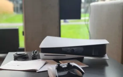 Konsola PlayStation 5 z kontrolerem i kablami na czarnym stole.