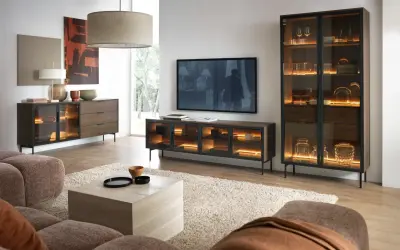 Modernes Wohnzimmer mit gemütlicher Couch. Ein Sideboard und Vitrinenschrank in grau und braun kombinieren, beleuchtet mit warmem Licht.