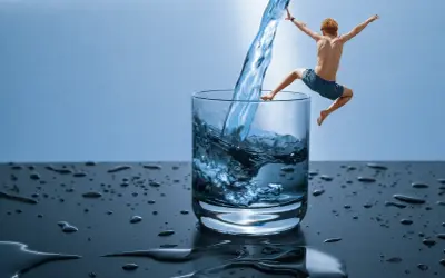 Chłopiec skacze do szklanki z wodą, jakby odkrywał, czym jest hydroterapia.