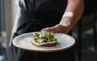 En kock presenterar en vacker tartar med örter och blommor, en delikatess från Torekov Hotell meny.