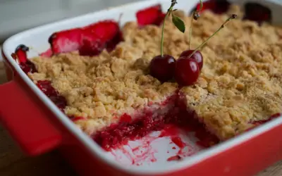 Un délicieux crumble fruits rouges, garni de cerises fraîches, sort du four.