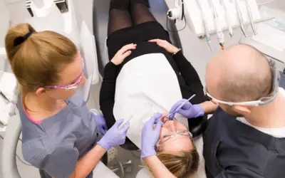 Dentyści wykonują fluoryzację zębów u pacjentki.