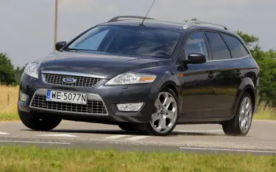Ciemnoszary Ford Mondeo MK4 2.0 TDCI na drodze, z widocznym polem zboża w tle.