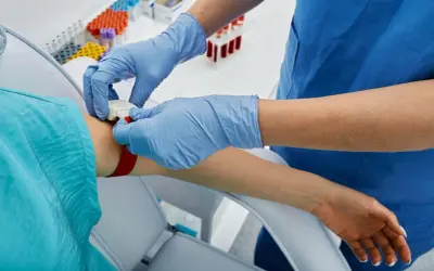 Pielęgniarka zakłada opaskę uciskową na rękę pacjenta, przygotowując się do pobrania krwi. To ważny krok, apo atorva na co.