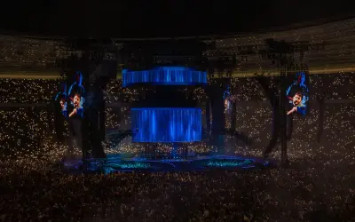Koncert Dawida Podsiadło, tłum z zapalonymi światłami, wielkie ekrany z wizerunkiem artysty.