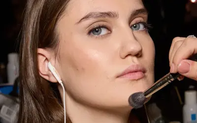 Applicazione di un pennello per il trucco sul viso, forse per schiarire il fondotinta o sfumare il blush.
