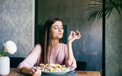 Frau genießt ihr Essen, als ob sie OMAD Fasten praktiziert und die einzige Mahlzeit des Tages zelebriert.