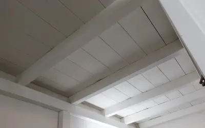 Deckenbalken und Holzpaneele, frisch weiß gestrichen, erhellen den Raum.