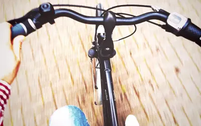 Widok z perspektywy rowerzysty. Ręka na kierownicy, dżinsy i droga w tle. Jak ustawić kierownicę w rowerze?