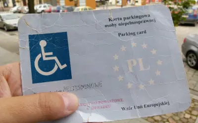 Karta parkingowa dla niepełnosprawnych, z symbolem wózka inwalidzkiego i oznaczeniem PL. Dokument wydany w Sieradzu, wzór Unii Europejskiej.