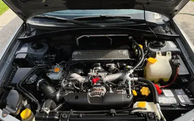 Silnik Subaru z widocznym zbiorniczkiem płynu chłodniczego. Sprawdzanie, ile mieści się płynu w chłodnicy, jest kluczowe dla jej prawidłowego działania.