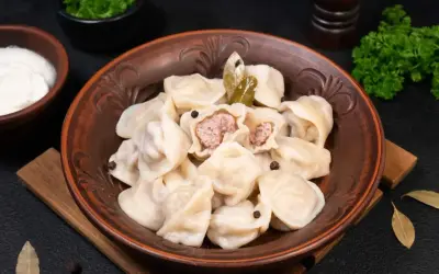 Pielmieni co to? Aromatyczne pierożki z mięsem, podane z kwaśną śmietaną i zieloną pietruszką. Pyszne danie!